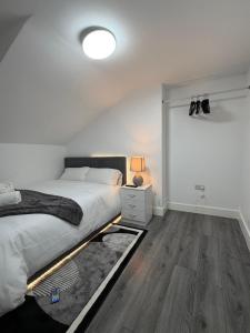 a bedroom with a bed and a lamp and wooden floors at Bpsairbnbltd in London +7 photos