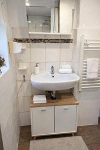 a white bathroom with a sink and a mirror at Ferienwohnung Flunder in Zempin