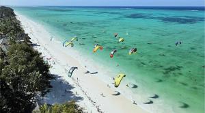 a group of people flying kites in the water on a beach at Villa Katerina-Zanzibar Apartment Paje in Paje +11 photos