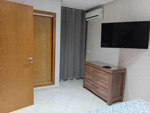 a room with a television on a wall with a dresser at Annakhil 30 in Oulad Akkou +3 photos