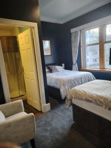 a bedroom with two beds and a chair and a window at Park Guest House in Inverness