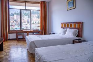 a hotel room with two beds and a window at Real Hotel Huascaran in Huaraz