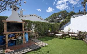 a backyard with a fireplace and green grass at Casa Tossa – Piscina, Vistas Mar y A/C (6 pax) in Tossa de Mar