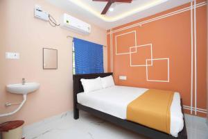 a small bedroom with a bed and a sink at Ramnath Residency in Rāmeswaram