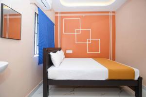a small bedroom with a bed with an orange wall at Ramnath Residency in Rāmeswaram