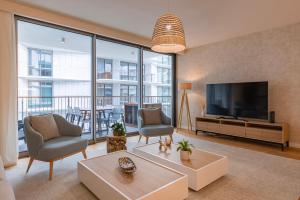 a living room with a tv and a large window at Bayline - Bezugo by Bedzy in Armação de Pêra