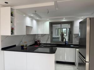 a kitchen with white cabinets and a stainless steel refrigerator at Villa neuve avec une grande terrasse in Dar Tahar Zaouch +15 photos