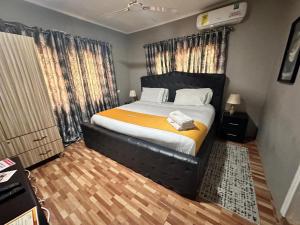 a bedroom with a large bed with a yellow blanket at Groove Vacation Homes in Kasoa