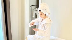 a woman in a white robe sitting in front of a mirror at Bayab Charming Rooms - Corso Garibaldi in Benevento