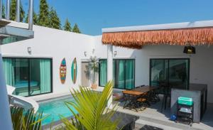 a house with a table and a swimming pool at Beloved Bliss Pool Villa Bangsaen พูลวิลล่าบางแสนมีสไลด์เดอร์ in Chon Buri