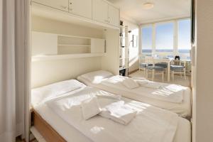 two beds in a room with a view of the ocean at Strandkieker in List