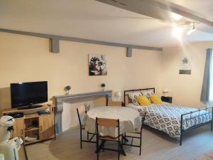 a bedroom with a bed and a table and a tv at L'Epinette in Torchefelon