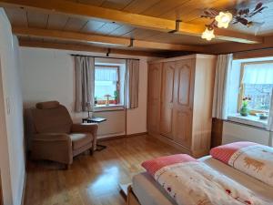 a bedroom with a bed and a chair and windows at Ferienwohnung Faschinggut in Rottau