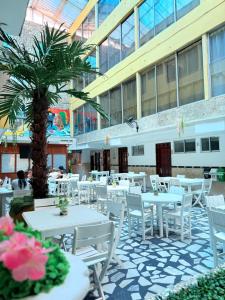 a restaurant with white tables and chairs and a palm tree at Hotel Toledo FL in Cartagena de Indias