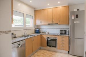 a kitchen with wooden cabinets and a stainless steel refrigerator at Casa con jardín en Besalú, ideal para familias in Besalú