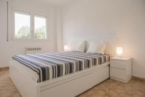a white bedroom with a bed with a striped blanket at Casa con jardín en Besalú, ideal para familias in Besalú