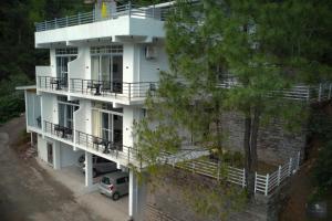 an aerial view of a white building with a parking lot at The Oaks - Scenic Couple Retreat in Kasauli with Private Balcony Views in Kasauli