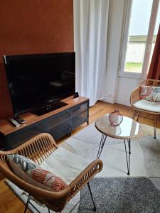 a living room with a television and a table and chairs at Les Arquebusiers in Chalons en Champagne