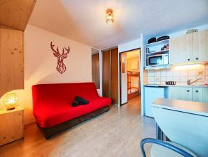 a bedroom with a red bed with a deer head on the wall at Charmant studio montagne - vue dégagée - pied des pistes in Mijoux
