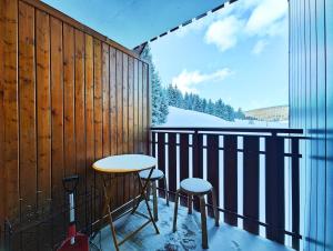 a balcony with a table and two stools and a window at Charmant studio montagne - vue dégagée - pied des pistes in Mijoux +11 photos