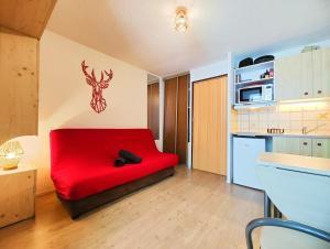 a red couch in a room with a kitchen at Charmant studio montagne - vue dégagée - pied des pistes in Mijoux