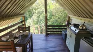 a screened in porch with a table and a stove at Jackal Cry River View Tent in Skeerpoort