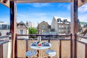 a balcony with a table and chairs and a view of a city at L'Échappée Belle de Houlgate 2 personnes in Houlgate