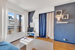 a living room with a couch and a tv at L'Échappée Belle de Houlgate 2 personnes in Houlgate