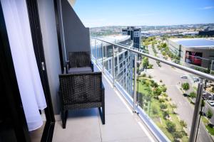 a chair on a balcony with a view of a city at SoftStay Ellipse Luxury Apartment in Midrand