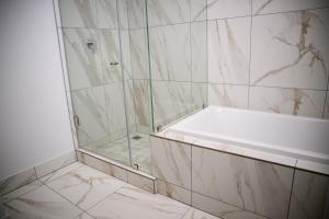 a bathroom with a shower and a bath tub at SoftStay Ellipse Luxury Apartment in Midrand