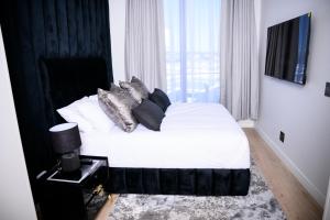 a bedroom with a bed with white sheets and pillows at SoftStay Ellipse Luxury Apartment in Midrand