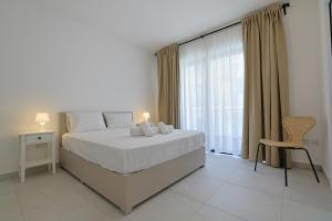 a bedroom with a bed and a chair and a window at Swieqi Malaika New Apt 6 in Is-Swieqi