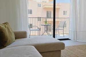 a living room with a couch and a balcony with a table at Swieqi Malaika New Apt 7 in Is-Swieqi