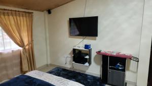 a bedroom with a bed and a flat screen tv on the wall at Villa Tungurahua in Huamboya