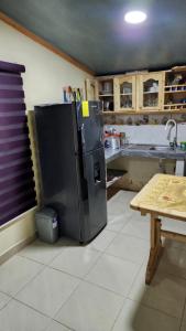 a kitchen with a black refrigerator and a table at Villa Tungurahua in Huamboya