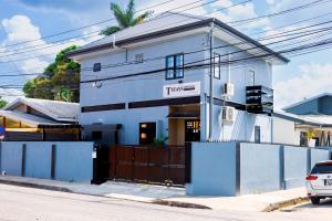 a white building with a sign that reads tempo at TStays Smart Hotel Courtyard, Gated Modern Stay in Port-of-Spain
