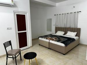 a bedroom with a bed and a chair and a table at Shri radha kripalu dham in Vrindāvan +6 photos