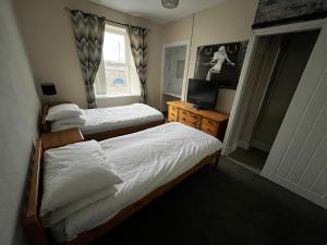 ein Schlafzimmer mit zwei Betten und einem Fernseher und einem Fenster in der Unterkunft The Innbetween in Pembroke Dock + 12 Fotos