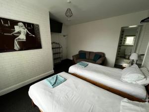 ein Hotelzimmer mit zwei Betten und einem Fernseher in der Unterkunft The Innbetween in Pembroke Dock