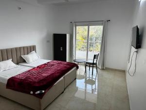 a bedroom with a bed and a table and a window at Shri radha kripalu dham in Vrindāvan
