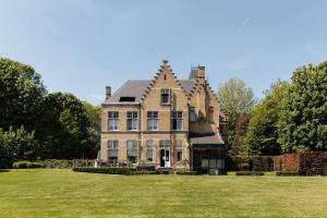 an old house with a grass field in front of it at Kasteel Ter Wallen - Boutique Hotel in Izegem