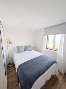 a white bedroom with a large bed and a window at Casa da Avó Elvina in Angra do Heroísmo
