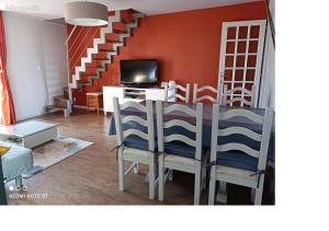 a dining room with a table with chairs and a television at L'Amandier in Néris-les-Bains