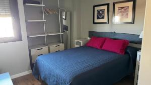 a bedroom with a blue bed with red pillows at Apartamento en Playa del Ingles CC Yumbo in Maspalomas +9 photos