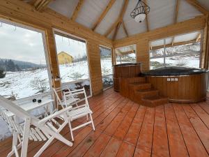 a screened in porch with a hot tub and rocking chairs at Aframe in Skhidnitsa