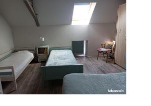 a small room with two beds and a window at L'Amandier in Néris-les-Bains