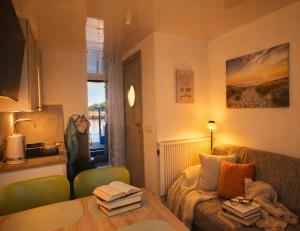 a living room with a couch and a table with books at ÖKO Budget Hausboot Retreat Morgenrot in Stralsund +16 photos