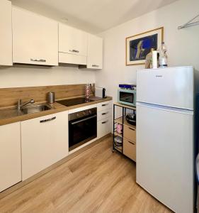 a kitchen with white cabinets and a white refrigerator at Maison Lake Maggiore Art Stay,central Baveno, 60 mt from Lake and Hotel Dino Congress Center in Baveno