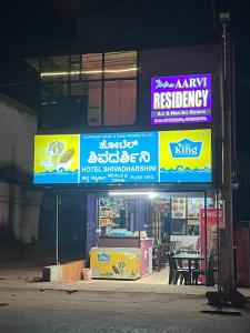 a restaurant with signs on the side of a building at Aarvi Residency in Māvalli