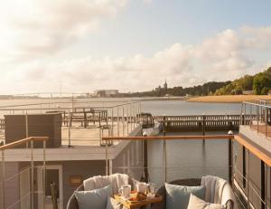 a balcony with chairs and a boat on the water at ÖKO Budget Hausboot Retreat Morgenrot in Stralsund
